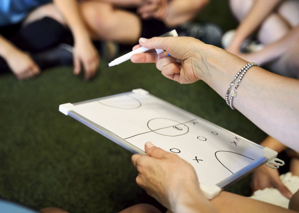 Coach with a whiteboard discussing game plan with soccer team