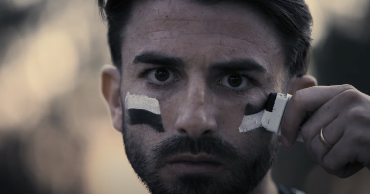 Greg Taylor rubbing black and white paint across his cheek after signing for PAOK